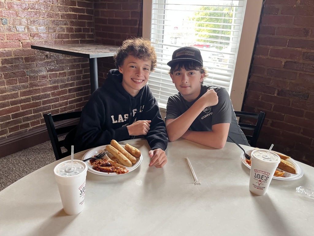 Two students are sitting at a table finishing their meal.