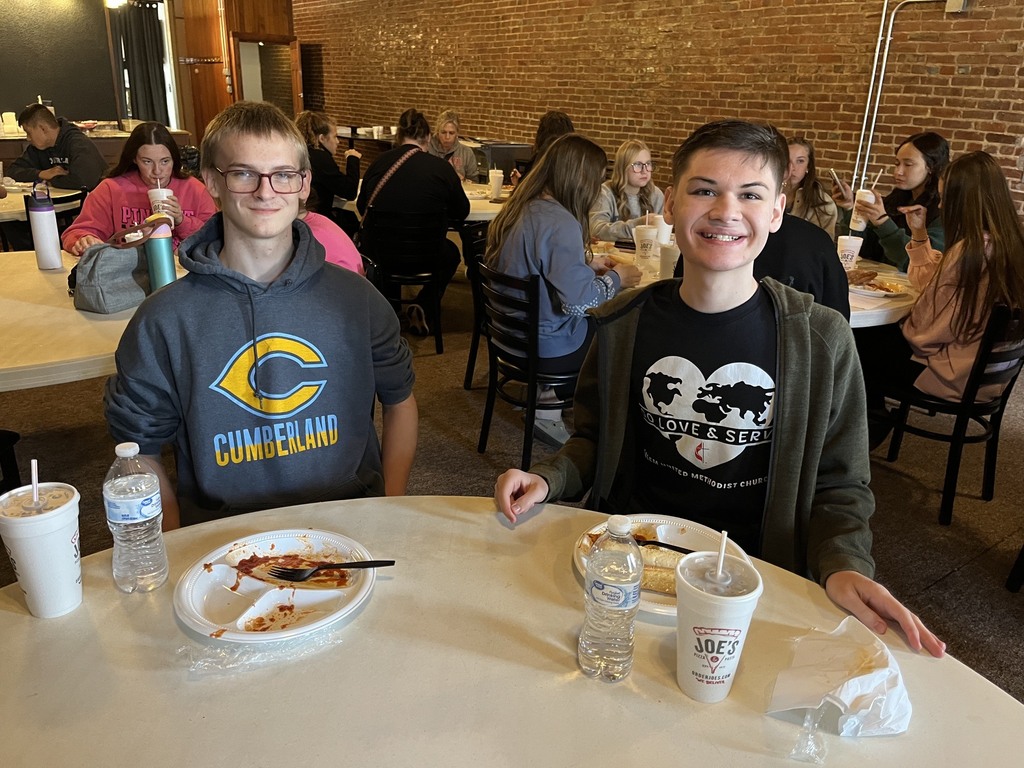 Two students are sitting at a table finishing their meal.