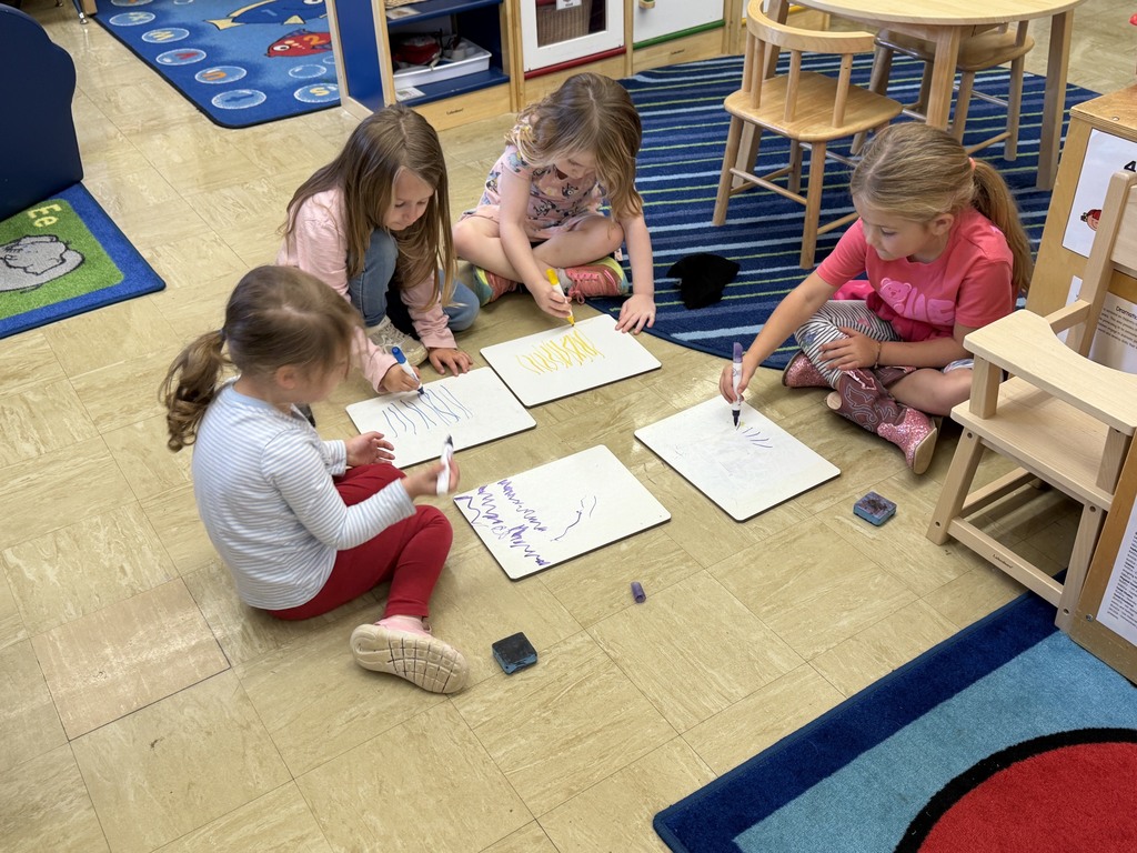Four students are drawing a tree on a white board. 