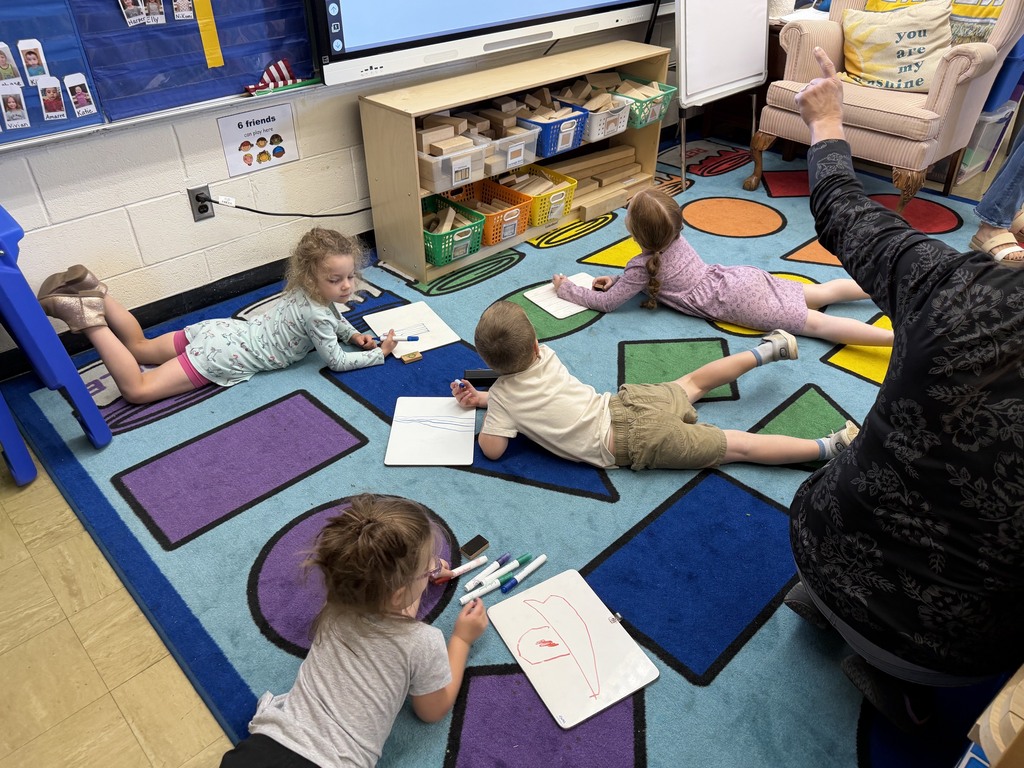 Four students are drawing a tree on a white board. 