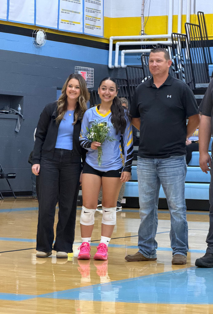 The player is standing on the court with parents. 