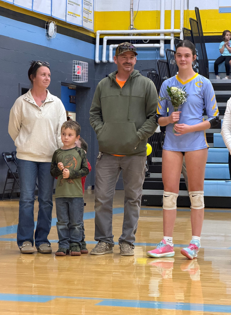 The player is standing on the court with parents. 