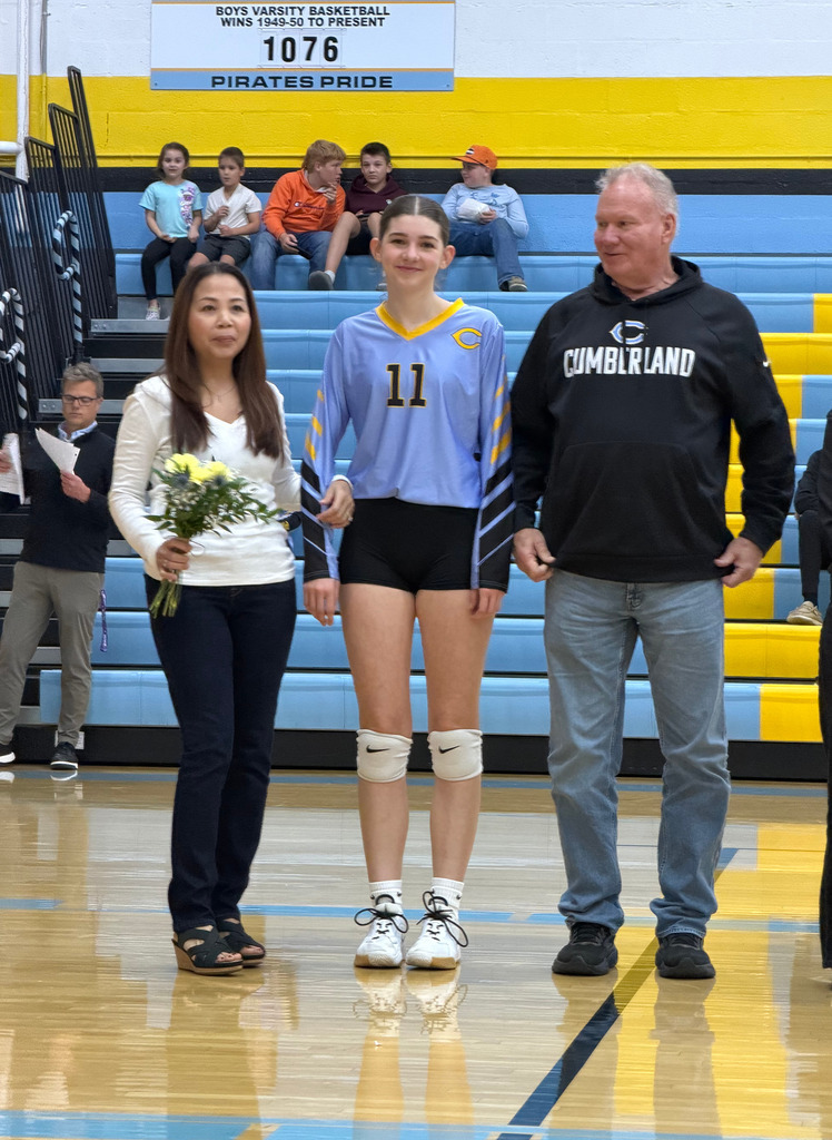 The player is standing on the court with parents. 