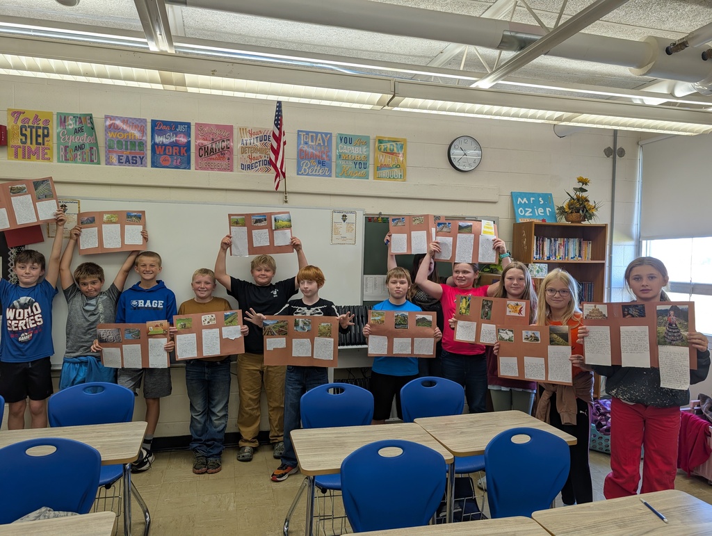 Students are standing in a row holding their codex projects. The projects are on brown construction paper. 