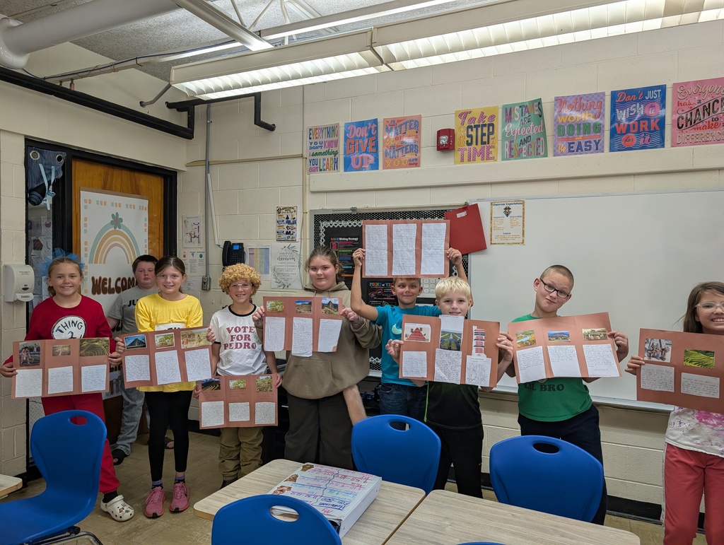 Students are standing in a row holding their codex projects. The projects are on brown construction paper. 