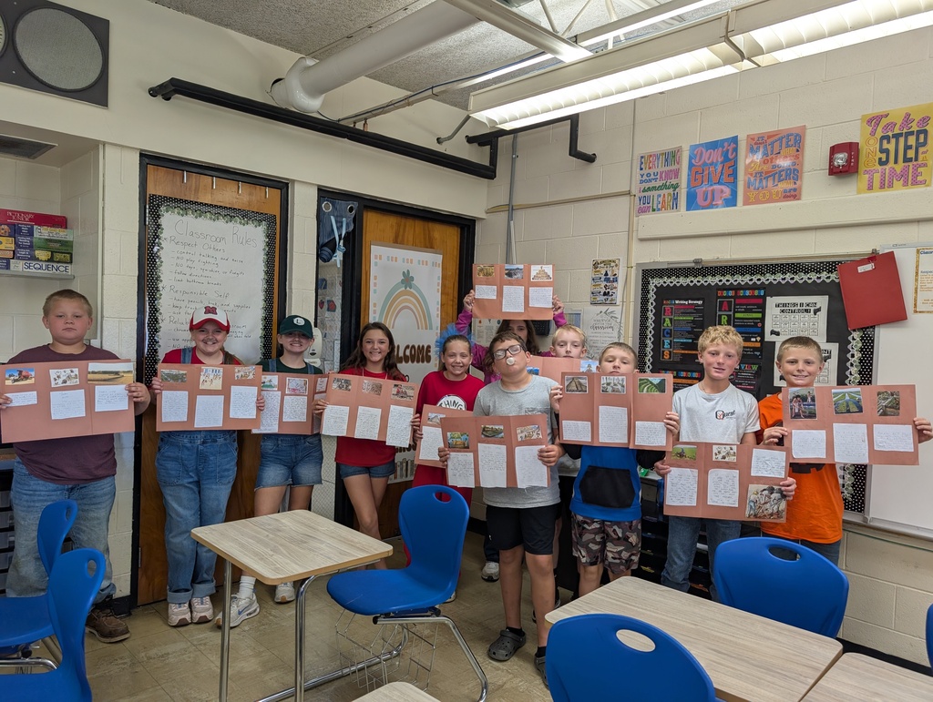 Students are standing in a row holding their codex projects. The projects are on brown construction paper. 