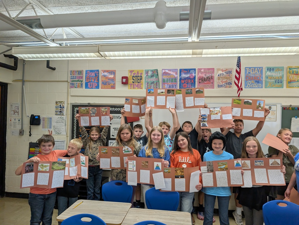 Students are standing in a row holding their codex projects. The projects are on brown construction paper. 