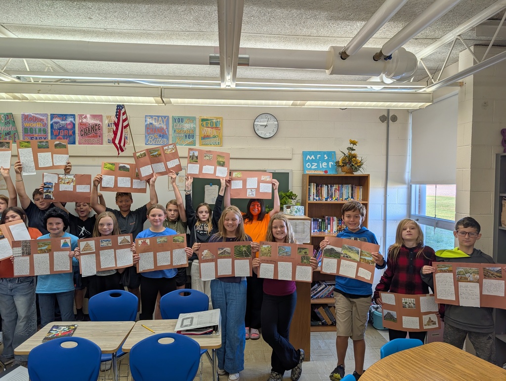 Students are standing in a row holding their codex projects. The projects are on brown construction paper. 