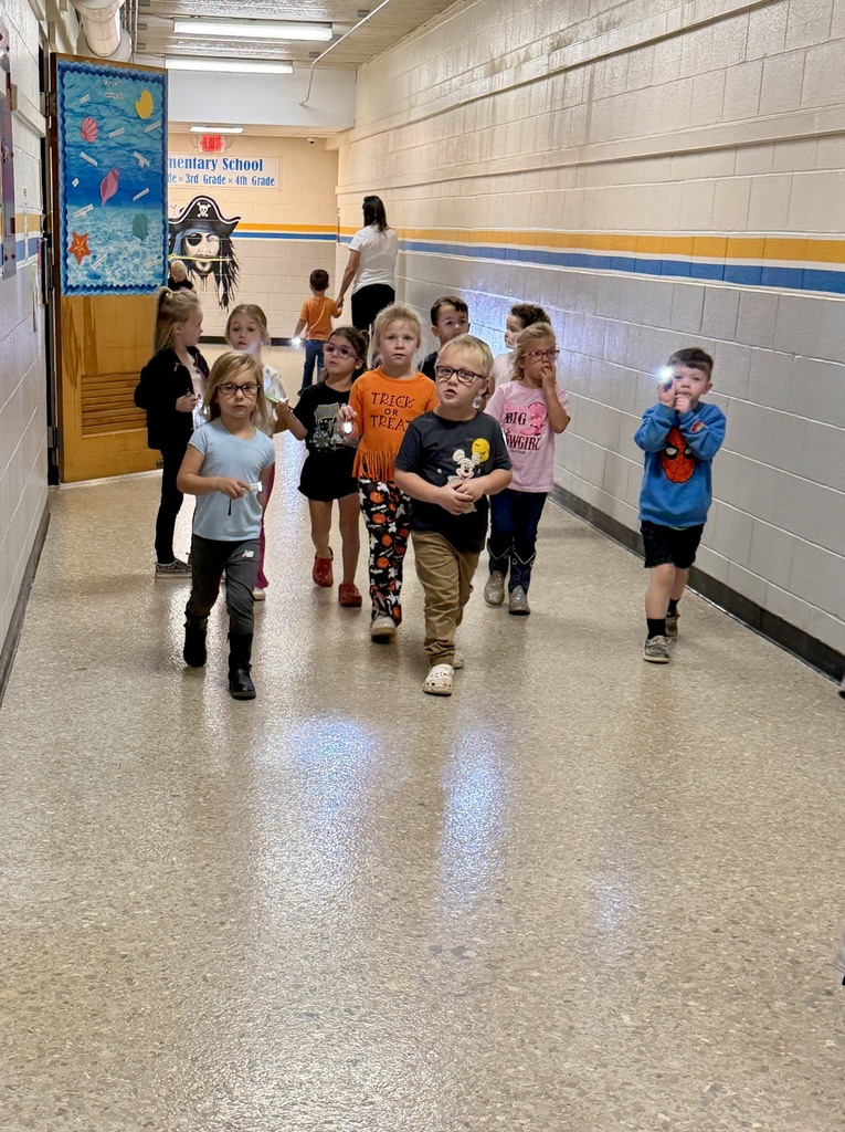 A group of students is walking down the hall shining their flashlights towards ghosts they find. 
