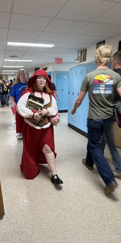 A student is walking in the hall dressed as little red ridding hood. 
