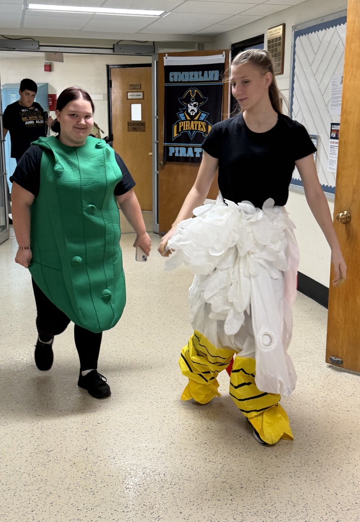 Two students are dressed up in the hallway. One is a pickle and another is an ostrich. 