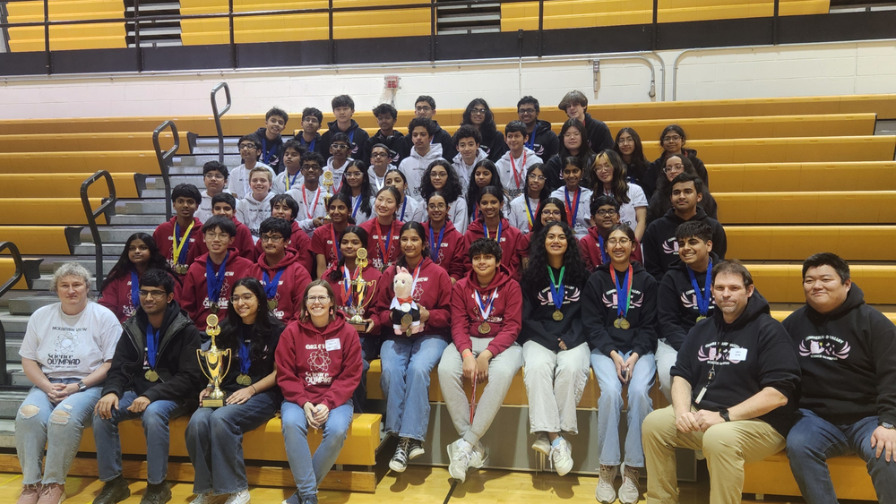 Group of CV Science Olympiad high school and middle school teams seated in bleachers holding medals and trophies from the Central Region Tournament.