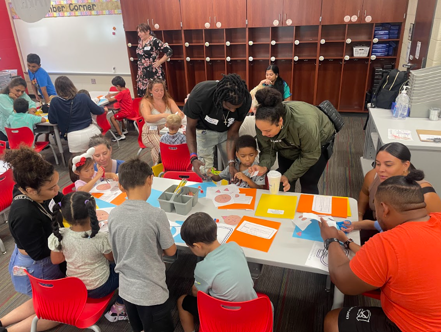 Parents and Kindergarten students work on a craft together.