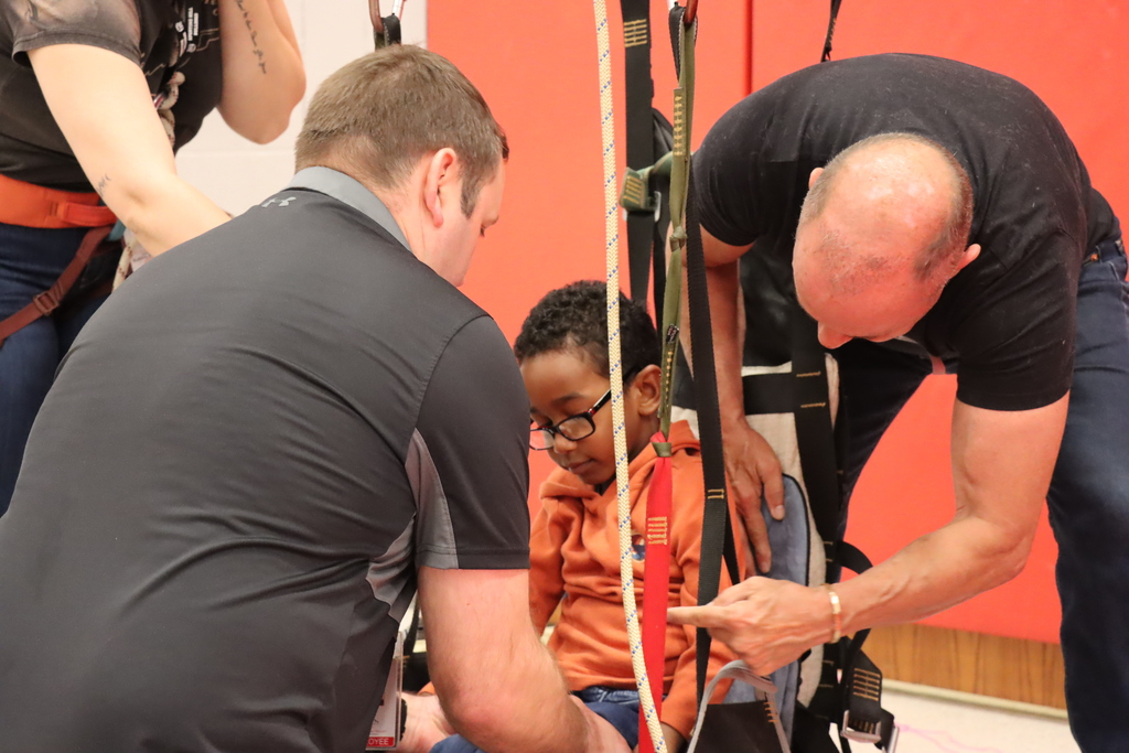 Student gets strapped into adaptive climbing chair.