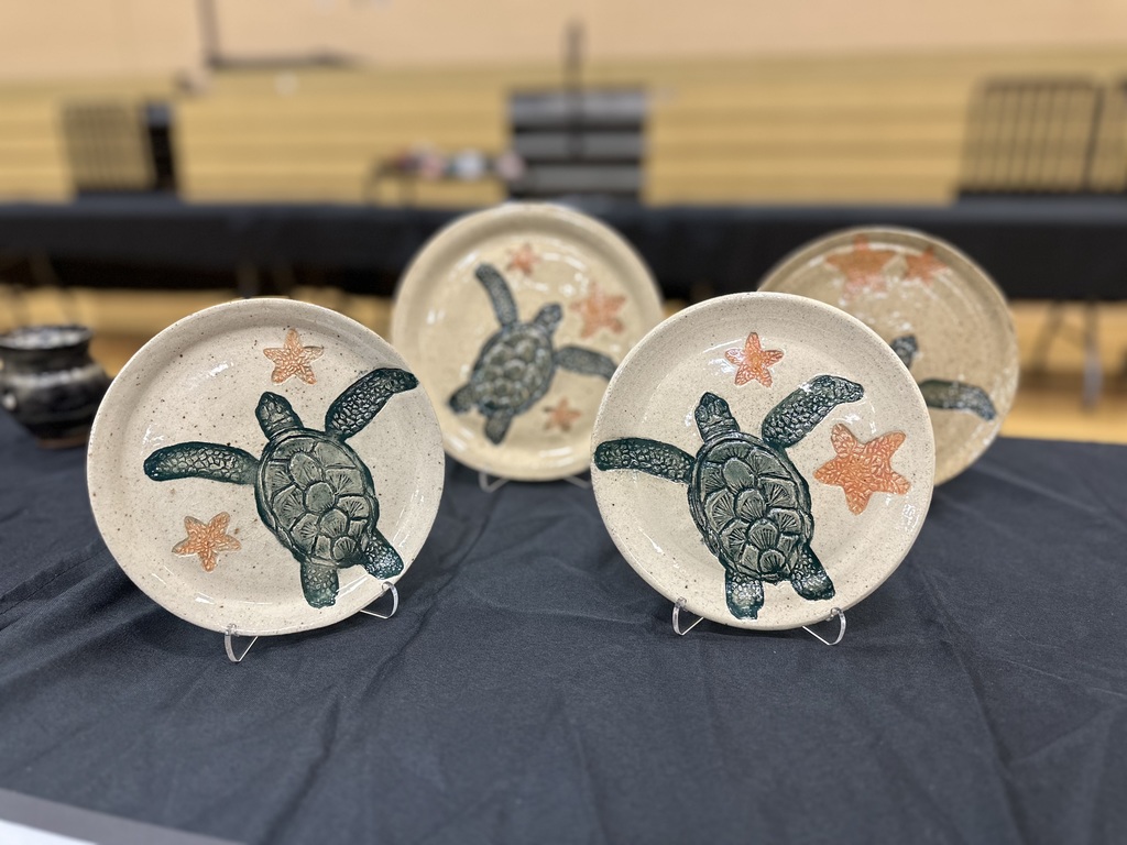 Four ceramic plates with sea turtle and starfish designs on a black tablecloth.