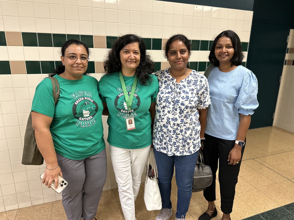 Four women standing in a hallway, two wearing 'Gators Pride' t-shirts.