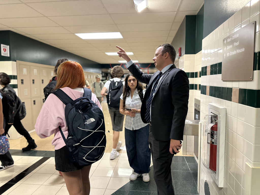 CVHS Principal in a suit directing students in hallway near lockers.