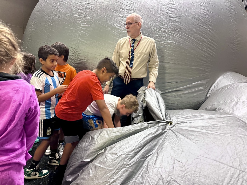 Children and an adult gather at the entrance of an inflatable dome at the Star Lab Planetarium.