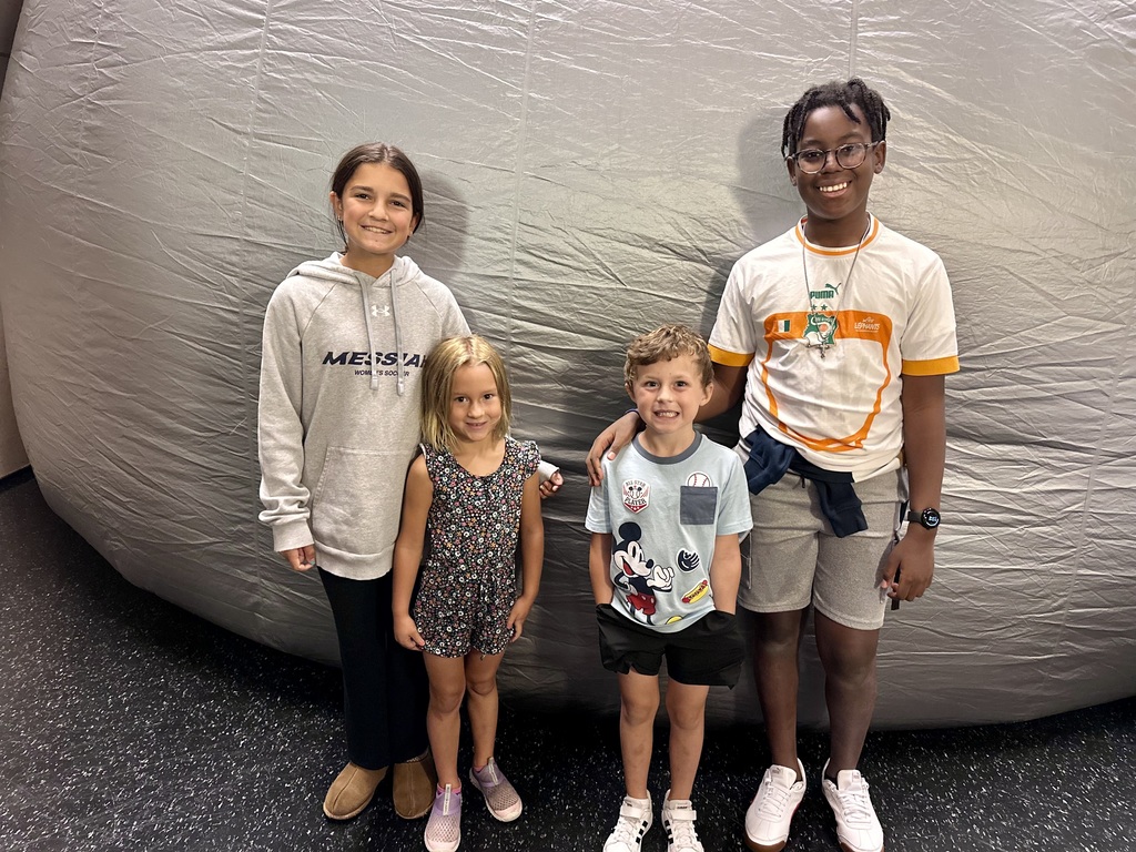 Four children stand in front of a large gray inflatable dome at the Star Lab Planetarium.