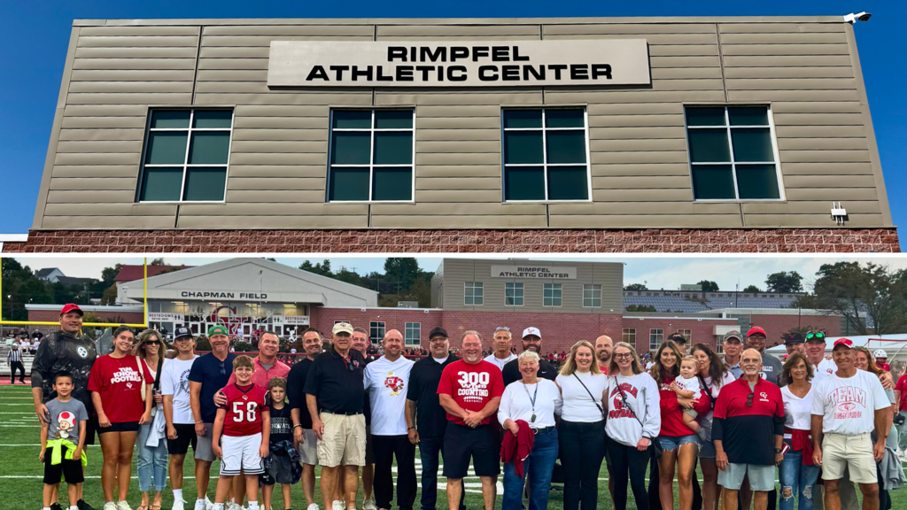 Group gathered on a sports field during the dedication of the Rimpfel Athletic Center, with Chapman Field sign in the background.