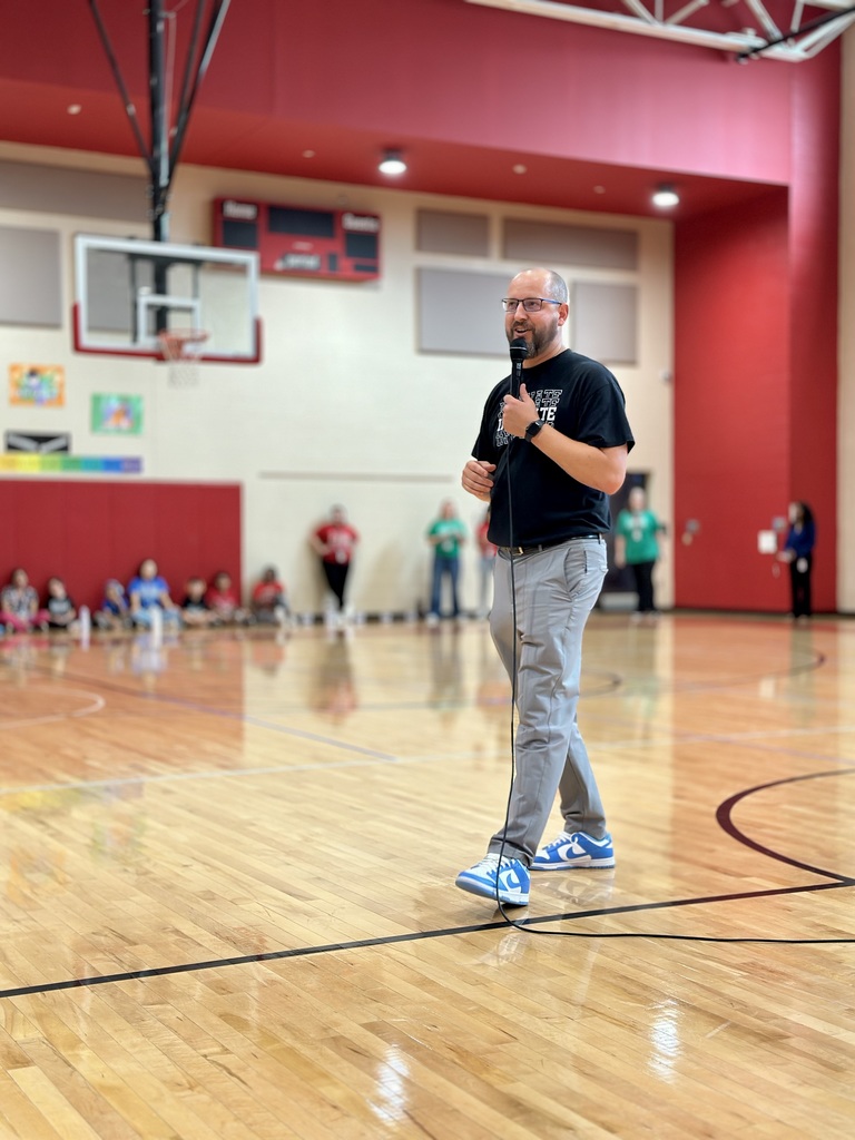 Dr. Runkle speaking into a microphone at the House assembly in a gymnasium.