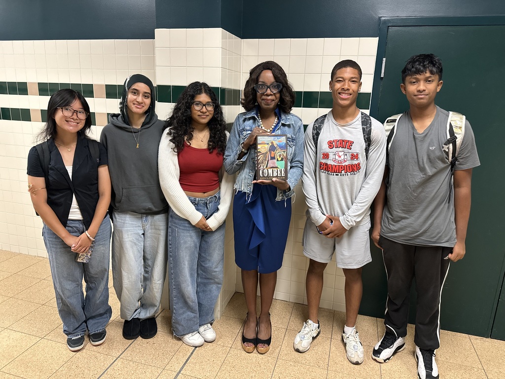 Dr. Edda Fields-Black stands with five students in a tiled hallway, holding her book "Combee.