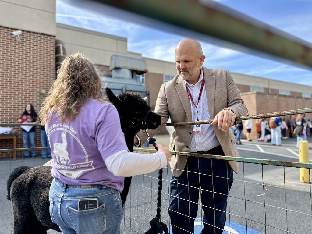 CV Superintendent Dr. Blanchard pets a black alpaca at AgVenture Day.