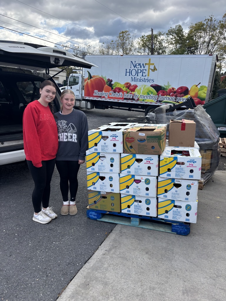 Two CV Cheerleaders stand with 1,000 pounds of food that they donated to New Hope Ministries in PA.