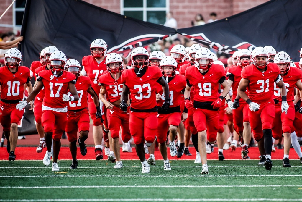 The 2025 Cumberland Valley Varsity Football team runs through a banner before the game.