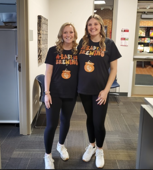 Two female teachers wearing matching shirts that say "A Baby Is Brewing"