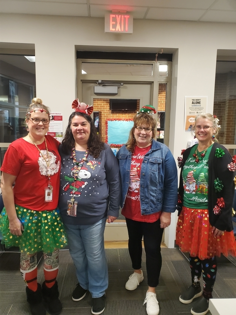 Four female teachers dressed in Christmas outfits with bows in their hair