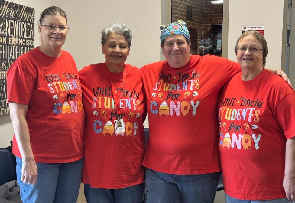 Four female teachers wearing matching red shirts that say "Will trade students for candy"
