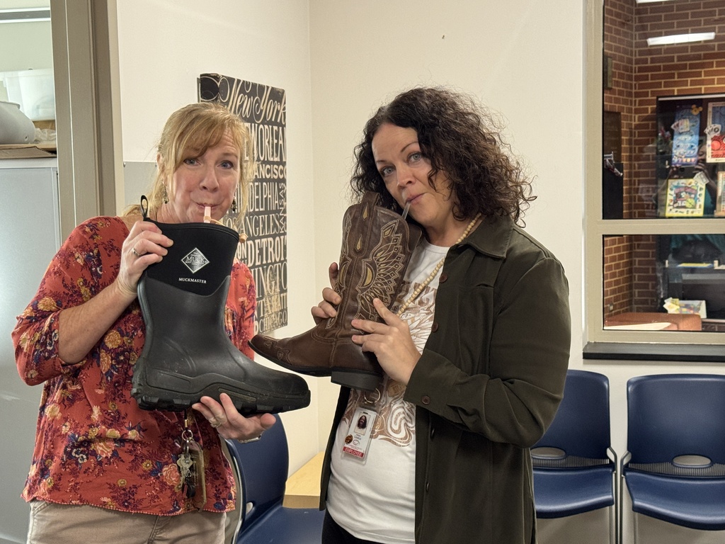Two female teachers drink out of boots
