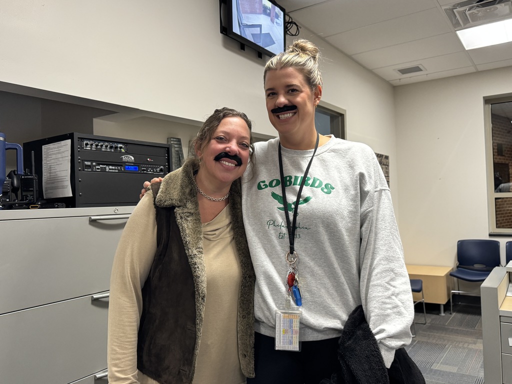 Two female specials teachers wearing fake mustaches and smiling