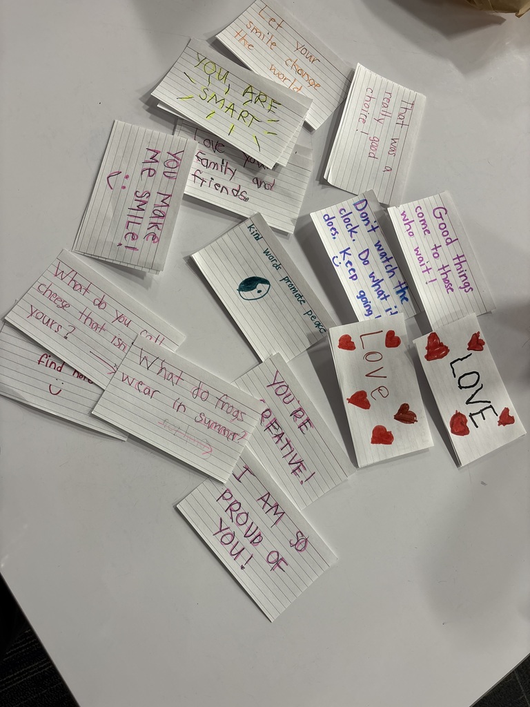 A collection of handwritten kindness notes on index cards with messages like “You make me smile,” “I am so proud of you,” and “Love,” decorated with hearts.