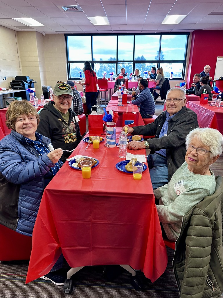 People sitting at a table, enjoying breakfast as a thank you, during a veteran's day assembly.