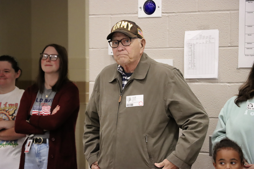 Army veteran stands to be recognized during a veteran's day assembly.