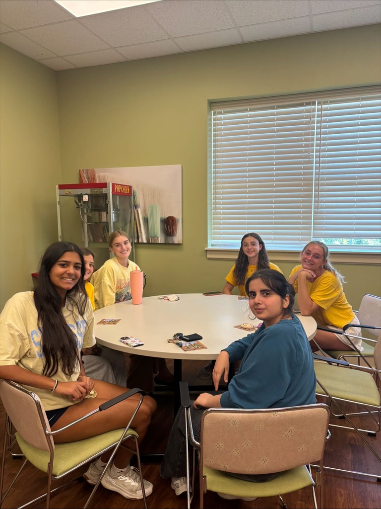 CVHS Golden Years Club students sitting around a table in a community room during volunteer time with seniors.
