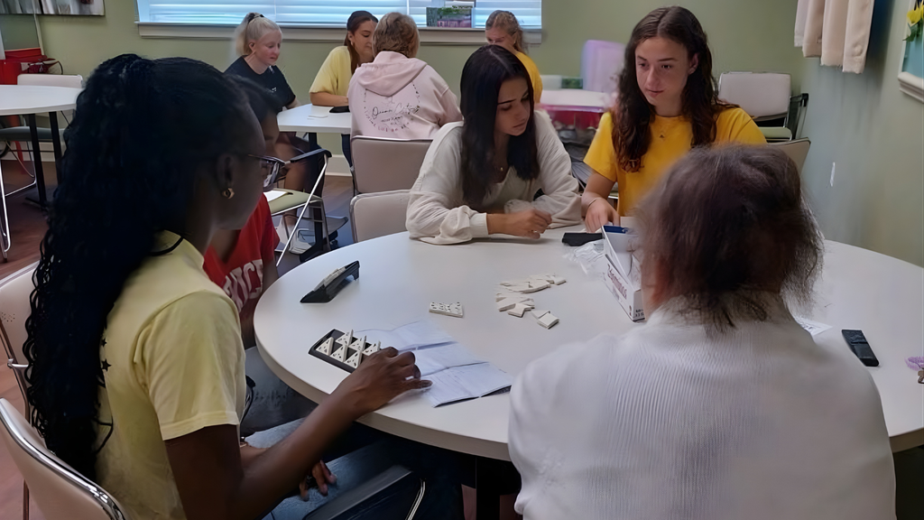 Students seated around a round table playing a tile-based game in a community room. The group is part of CVHS’ Golden Years Club, which volunteers with the senior community.