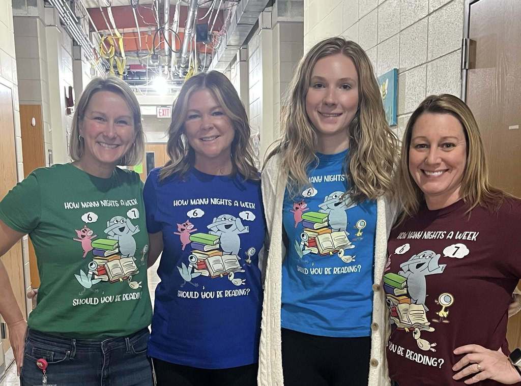 Four teachers wearing colorful shirts with cartoon animals and books that read “How many nights a week should you be reading?” featuring numbers 6 and 7, celebrating the 67th day of school. Provide your feedback on BizChat
