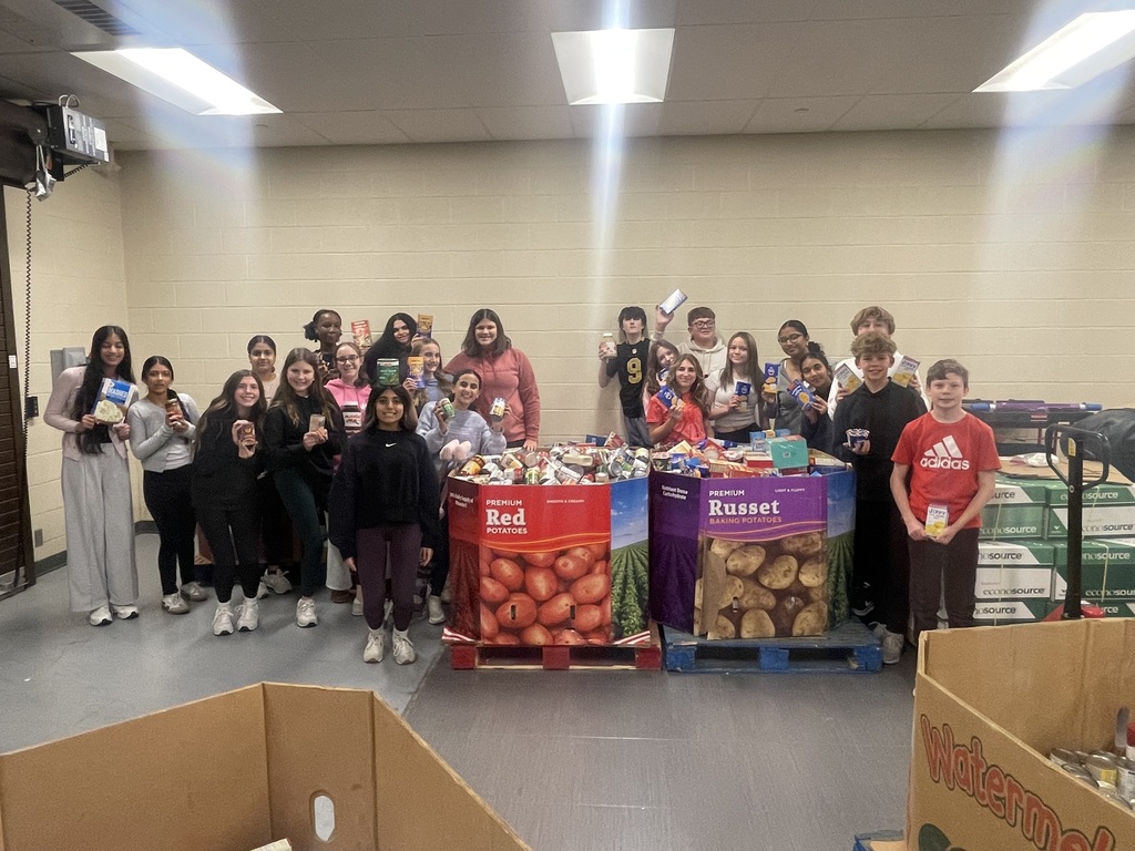 Group of Mountain View Middle School students standing behind large boxes filled with canned goods and packaged food during the school’s canned food drive.
