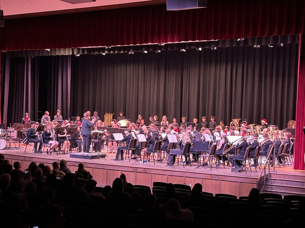 A full student band performs on stage in Eagle View Middle School’s new auditorium during the winter concert, led by the conductor at center.