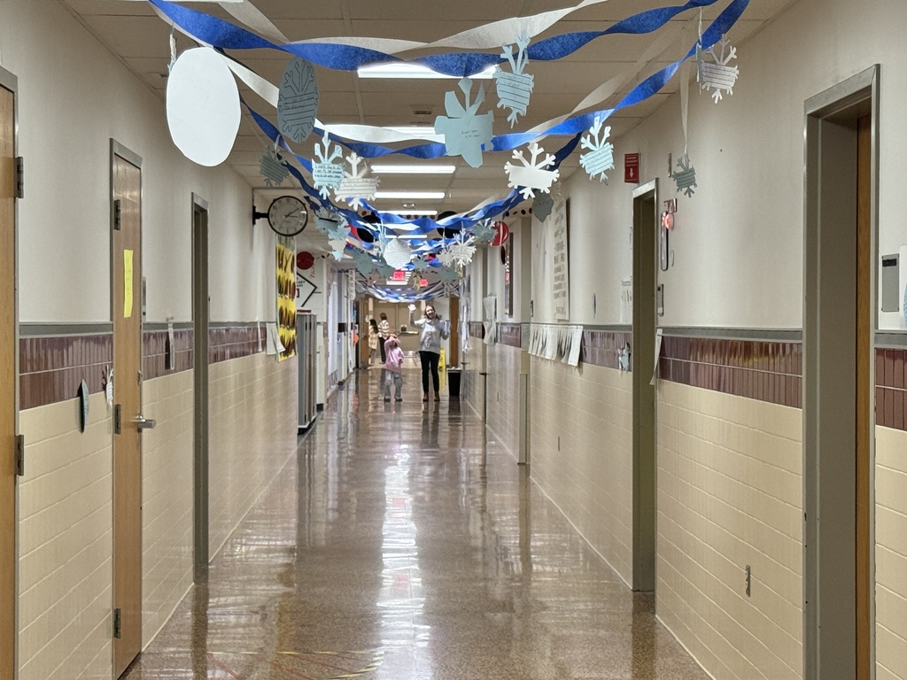Hallway filled with blue and white streamers and snowflakes with female teacher and student waving hello.