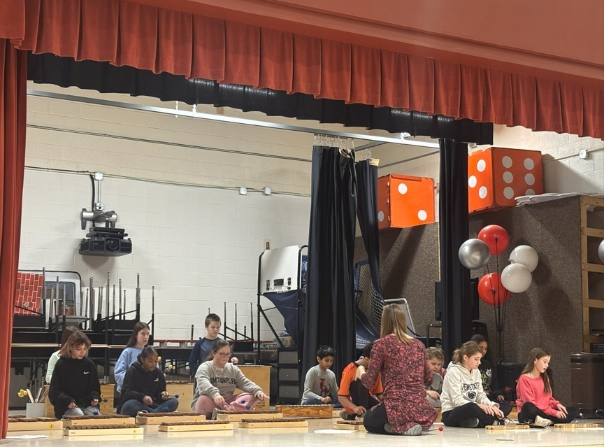 Teacher and students on stage practicing instrument