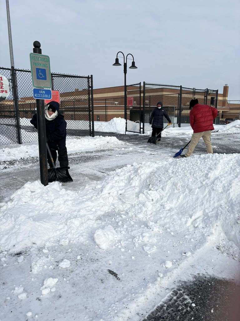 CVSD Maintenance and Facilities crews clearing off sidewalks on campus with shovels, moving snow into piles.