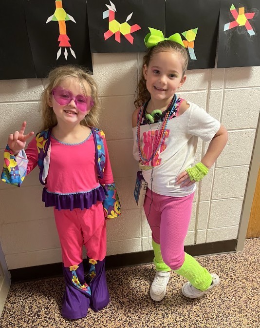 Two female students dressed in neon pinks and greens, excited for Decades Day at school.