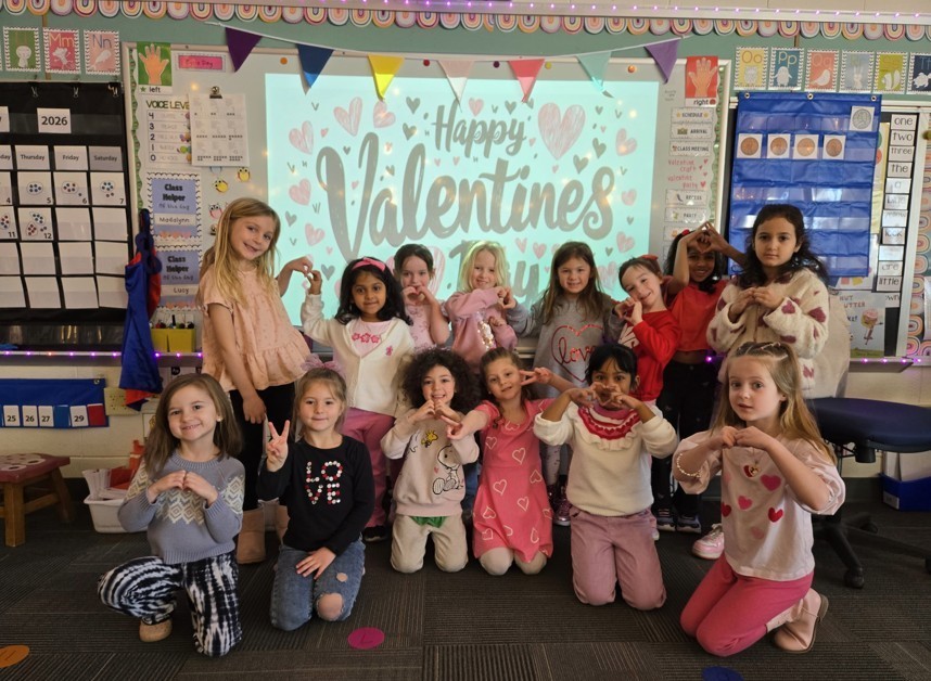Elementary school girls standing together and smiling for class Valentine's party.