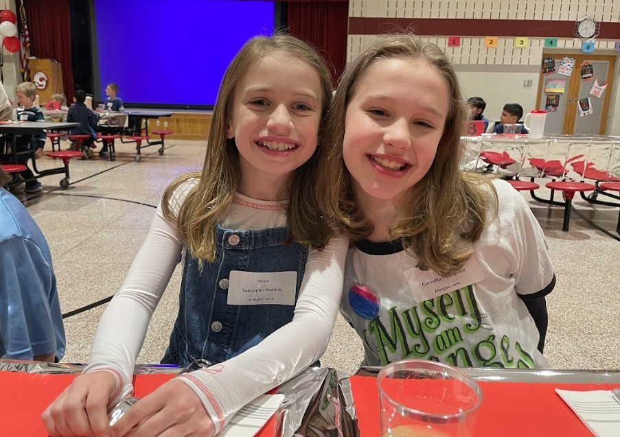 Two female students, smiling proudly at the camera.