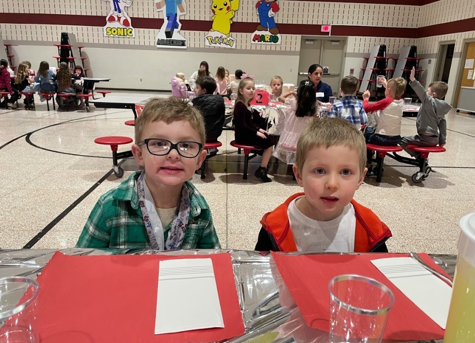 Two small boys, one wearing glasses, smiling.
