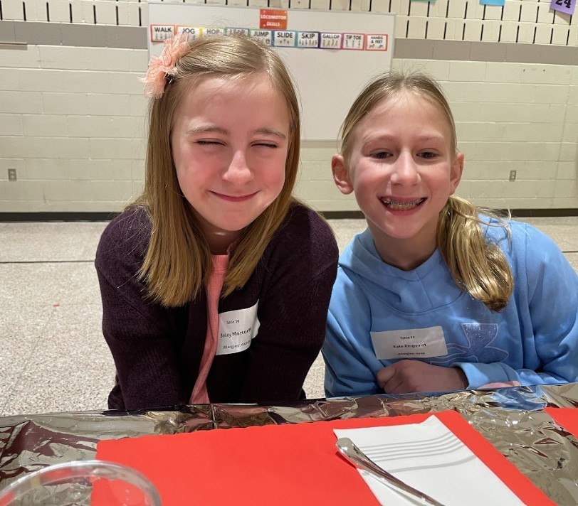 Two female students with blonde hair, smiling gleefully at the camera.